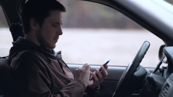 Homem europeu usa smartphone, sentado na cabine do carro . — Vídeo de Stock