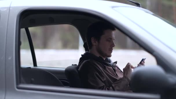 Οδηγός χρησιμοποιούν smartphone, κάθεται στο αυτοκίνητο. — Αρχείο Βίντεο