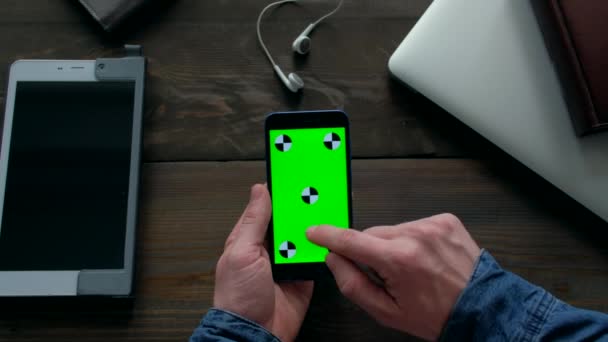 Mani dell'uomo utilizzando smartphone con schermo verde su tavolo in legno. — Video Stock