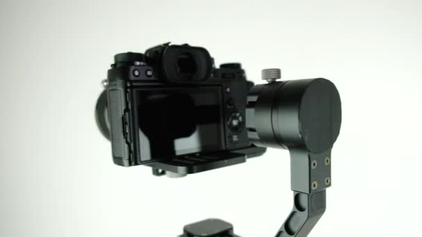 Gimbal s digitálním fotoaparátem se otáčí na bílém pozadí. — Stock video