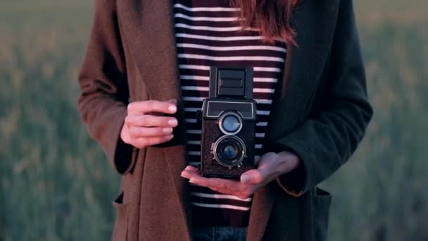 Handen van meisje staat in veld Holding Vintage camera. — Stockvideo