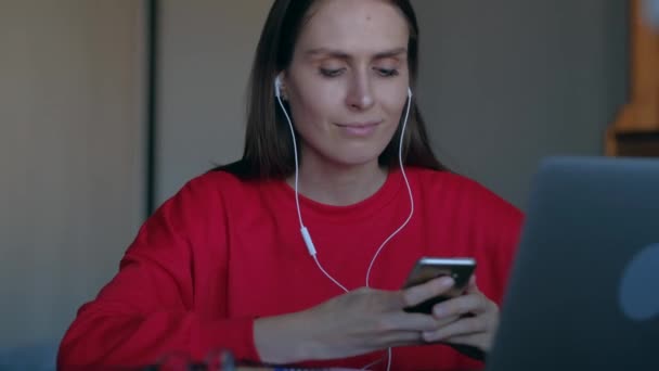 Feminino ouvir música com fones de ouvido e dançar sentado atrás do local de trabalho . — Vídeo de Stock