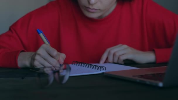 Schattige vrouw overschrijft in Kladblok informatie van de laptop. — Stockvideo