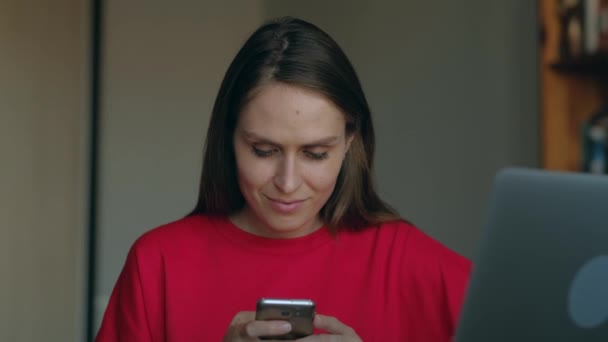 Mädchen mit rotem Sweatshirt kommuniziert mit ihren Lieben zu Hause per Smartphone. — Stockvideo
