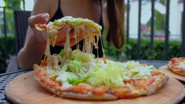 Kadın sıcak pizza streç peynir ile iştah açıcı dilim alır.