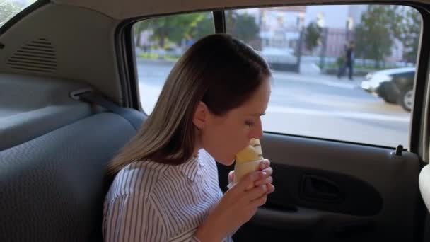 Morena bonito comer sanduíche no carro de táxi . — Vídeo de Stock