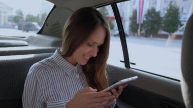 Arka koltukta araba taksi oturan bir dijital tablet kullanan kadın.