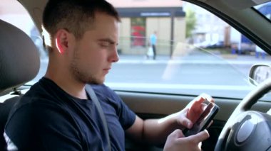 Sürücü arabada akıllı telefon kullanıyor.