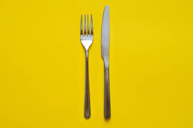 Çatal ve bıçak sarı arka plan üzerinde izole. 