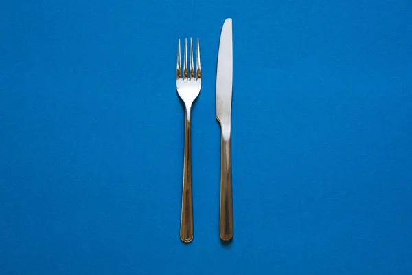 Tenedor y cuchillo aislados sobre fondo azul . — Foto de Stock