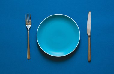 Mavi arka planda izole edilmiş renkli plaka çatalı ve bıçağı. 