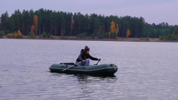 A female sportsman rows and swims on a rubber boat on lake. — Stock Video