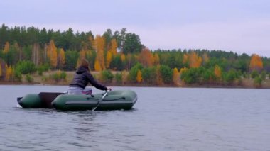  Güzel bir sonbahar ormanında, büyük bir gölde, kauçuk bir teknede yüzen bir kadın..