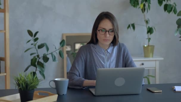 Beautiful woman in eyeglasses work on laptop in office. Medium shoot. — ストック動画