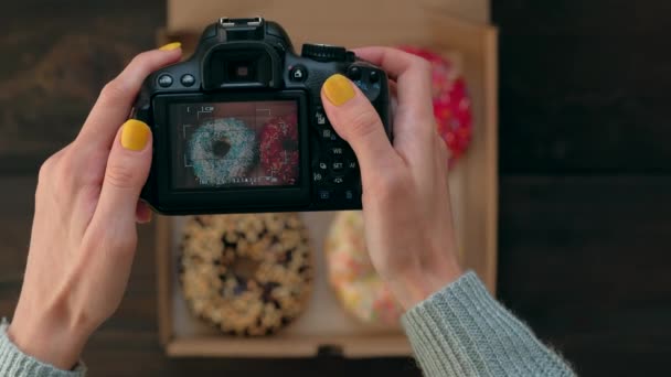 Las manos de las mujeres toman fotos con la cámara de fotos de deliciosos donuts en caja . — Vídeos de Stock