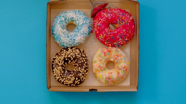 Toma la rosquilla de la caja de rosquillas sobre fondo azul. Donut de moda surtido . — Vídeos de Stock