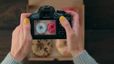 Kadın eli, kutudaki lezzetli donutların fotoğraf makinesiyle fotoğraf çeker..