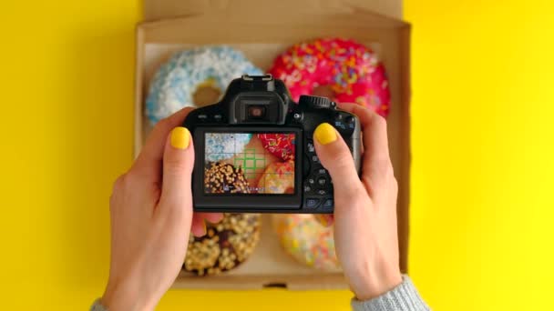 Mãos femininas tirar fotos com câmera de fotos de deliciosos donuts na caixa . — Vídeo de Stock
