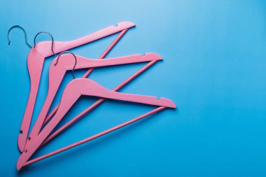 Pembe boş ahşap elbiseler pastel mavi arka planda asılı..