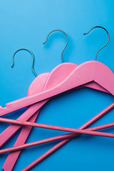 Pembe boş ahşap elbiseler pastel mavi arka planda asılı..