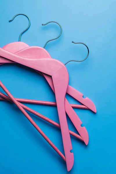 Pembe boş ahşap elbiseler pastel mavi arka planda asılı..