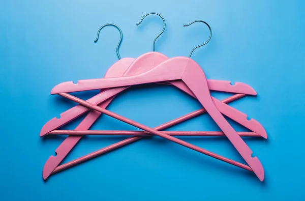 Pembe boş ahşap elbiseler pastel mavi arka planda asılı..