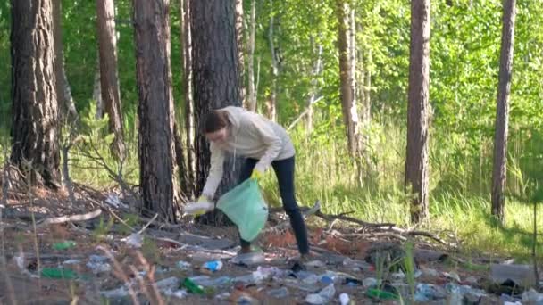 Volunteer collects plastic bottles outdoors. — Stock Video