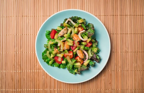 Draufsicht - Salat mit Meeresfrüchten auf Farbteller Stockbild