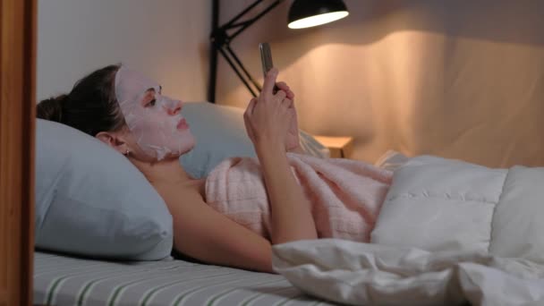 Kobieta pielęgnacja skóry zabieg kosmetyczny przeglądać telefon. — Wideo stockowe