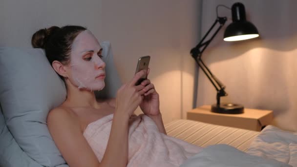 Žena péče o pleť kosmetické procedury procházet telefon. — Stock video