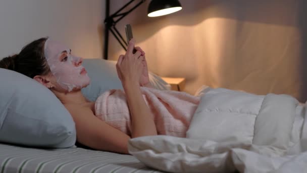 Žena péče o pleť kosmetické procedury procházet telefon. — Stock video