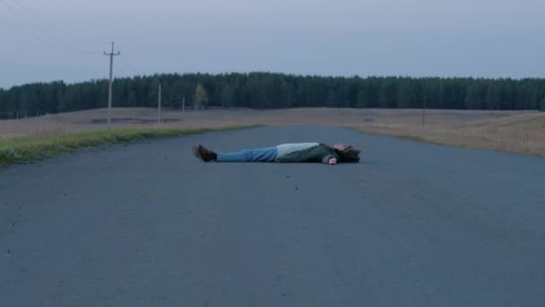 Γυναίκα ξαπλωμένη στον ασφαλτοστρωμένο δρόμο. — Αρχείο Βίντεο