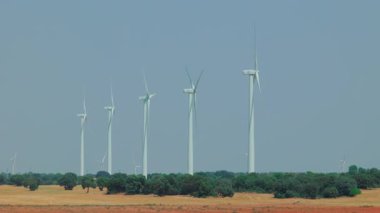 Rüzgâr türbinleri açık kırsal alanda çoklu yel değirmenleriyle dönüyor.