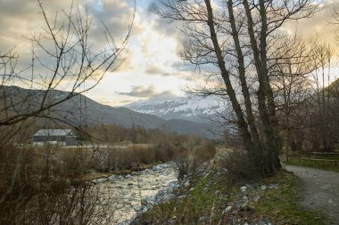 Dağ nehri karla kaplı dağların arkasında.