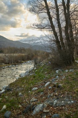 Dağ nehri karla kaplı dağların arkasında.