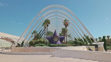 Valencia 'daki Umbracle' ın ön görüntüsü büyük beyaz kemerleri, palmiye ağaçları ve ortasında mor yıldız şeklinde bir heykeli var. Sanat ve Bilim Şehri 'nin modern ve kültürel simgesidir. Valencia, İspanya - 17 Eylül 2025