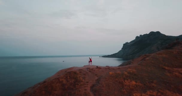 Picos de las Montañas, Sunset Sea y mujer joven. Épica en el borde del valle de la montaña con rocas y destellos de sol. Vuelo en avión no tripulado 4k. Establecimiento aéreo. Europa naturaleza verde. Película vintage colores . — Vídeo de stock