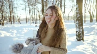 Kazak giyen çekici genç kız ceket giydiri. Kar yığınları ve karlı bir orman bir arka plan üzerinde sıcak giysiler kıvırcık genç kadın. Kış manzarası. Kuzey soğuk havası. Güzel arka plan.