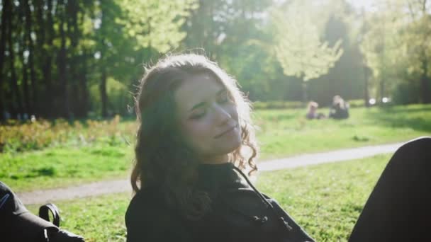Κοντινό πλάνο της νεαρής όμορφης κοπέλας που κάθεται στο πάρκο με πολύχρωμο μακιγιάζ. Προνοητικά συναισθήματα — Αρχείο Βίντεο