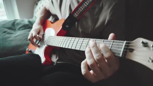 Primer plano del joven tocando en la guitarra eléctrica roja funk o blues al lado de la ventana. Imágenes en cámara lenta — Vídeos de Stock