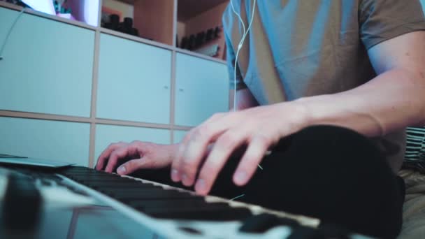 Νεαρός καυκάσιος που κάθεται στην κρεβατοκάμαρά του και παίζει σε πληκτρολόγιο ή συνθεσάιζερ MIDI και κάνει ηλεκτρονική μουσική.Dj βίντεο αργής κίνησης — Αρχείο Βίντεο