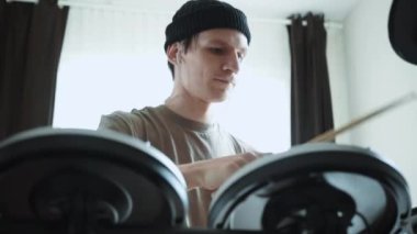 Genç erkek davulcu evde elektronik bateri çalıyor. Rock müzik performansı. Perküsyon aletleri dersi 60 fps yavaş çekimde olabilir