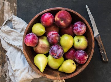 Çeşitli olgunlaşmış meyve - elma, armut ve Erik bir ahşap rustik koyu bir masaya kase. Üstten görünüm. Çiftlik hasat kavramı