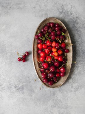 Çeşitli yaz tatlı kiraz ve vişne gri masada rustik metal plaka üzerinde.