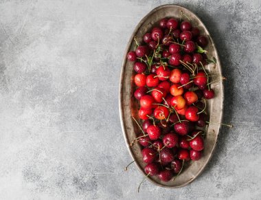 Çeşitli yaz tatlı kiraz ve vişne gri masada rustik metal plaka üzerinde.