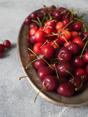 Çeşitli yaz tatlı kiraz ve vişne gri masada rustik metal plaka üzerinde.