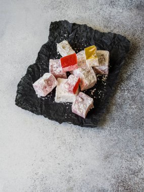 Geleneksel oryantal tatlı Türk lokumu gri arka plan üzerinde siyah kağıt üzerinde.