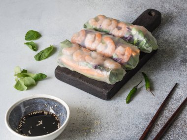 Üç Vietnamca spring rolls - havuç, salatalık, Mısır salata, kırmızı lahana, otlar ve karides ahşap bir kara tahta üzerinde.