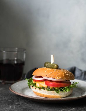 Domates soslu klasik çörekler taze ev yapımı Hamburger marul, turşu, peynir, soğan koyu arka plan üzerinde gri zanaat kil plaka üzerinde