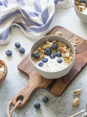 Granola ve yoğurt, yaban mersini ve badem ahşap tahta üzerinde top. Sağlıklı kahvaltı.